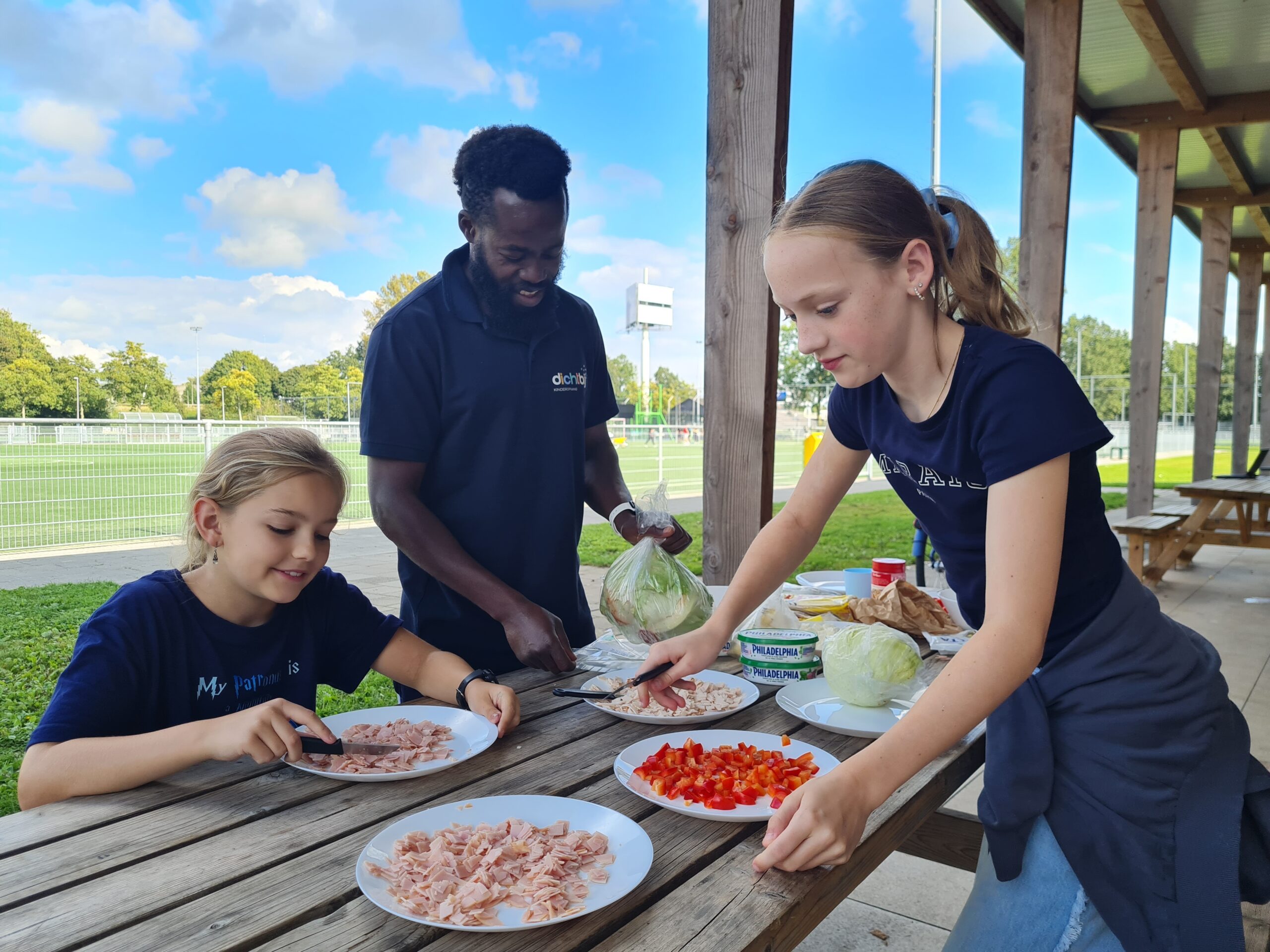 Kinderen en pedagogisch professional maken buiten eten klaar bij Dichtbij BSO Teens in Vianen